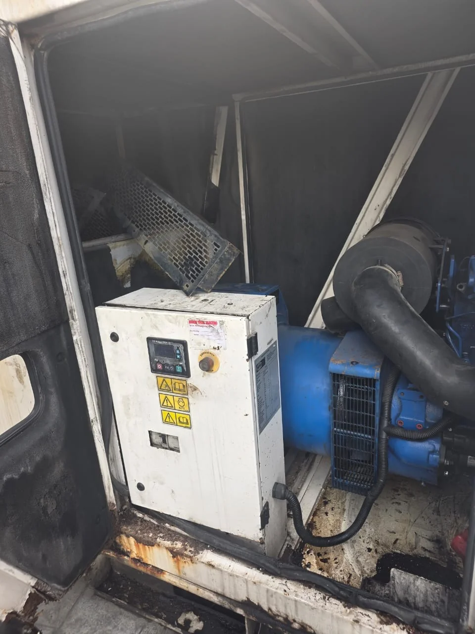 Generator control cabinet and blue engine inside an enclosure